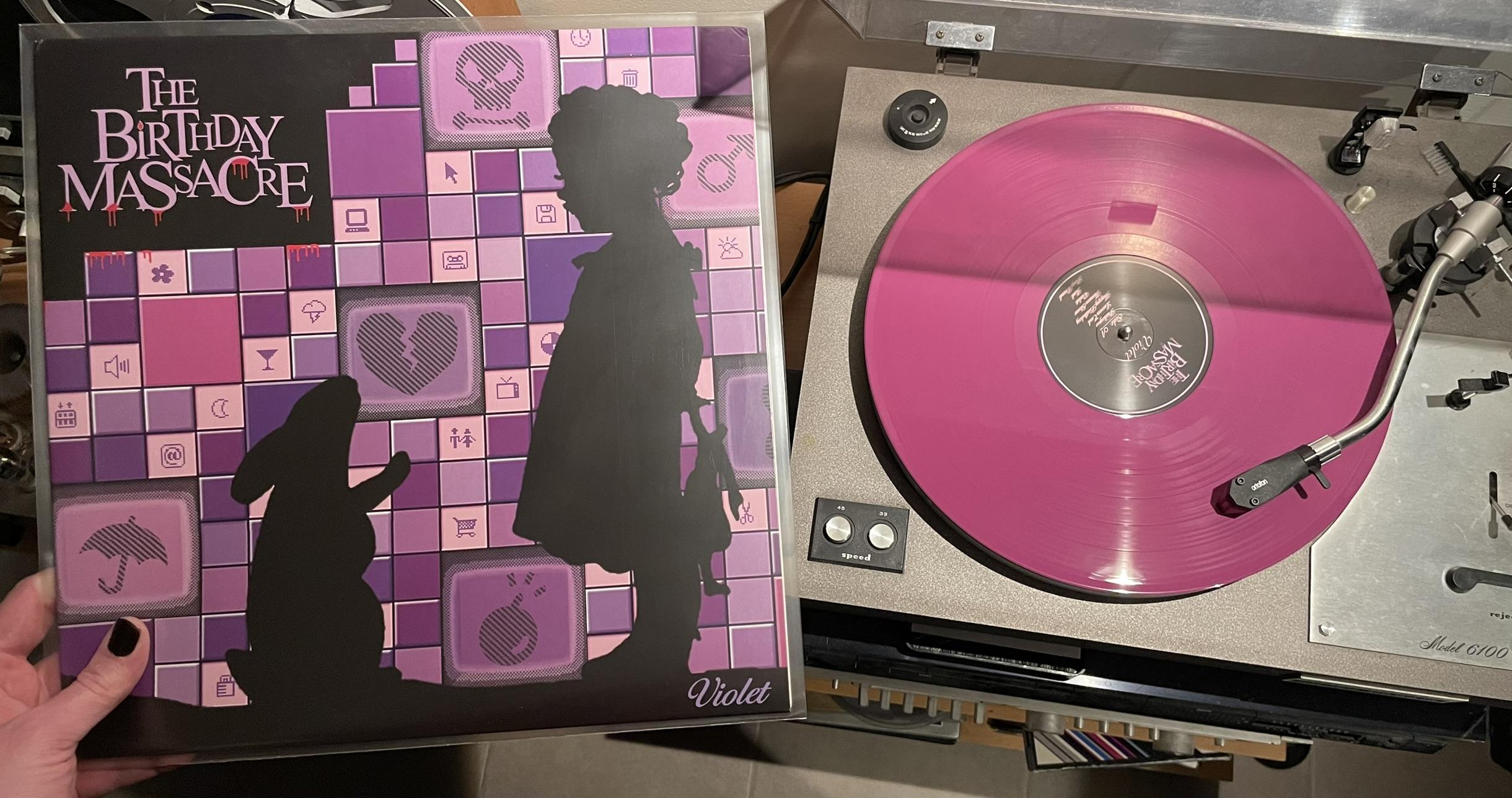 Le vinyle de couleur violette sur la platine vinyle en train d'être lu et la pochette du vinyle de l'album avec les couleurs violettes, le lapin et un enfant avec une poupée et le logo ensanglanté du groupe.